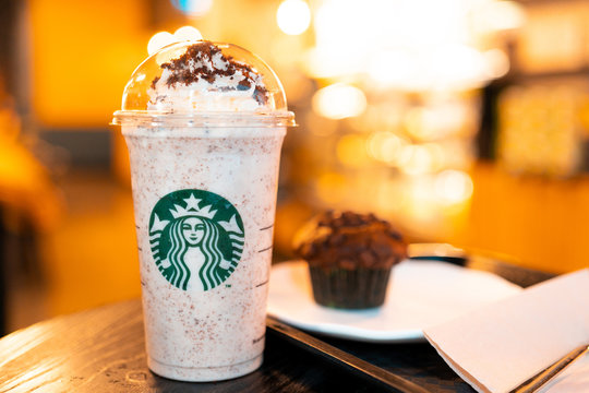 Melbourne, Australia - August 20, 2019: Close up Starbuck cold smoothie coffee cup and Chocolate cupcake with blur Starbuck interior for background.