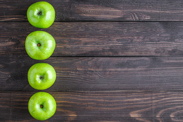 Ripe green apples and apple slices on old wooden background.Vegetables for diet and healthy eating.Organic food. Place for text. Top view