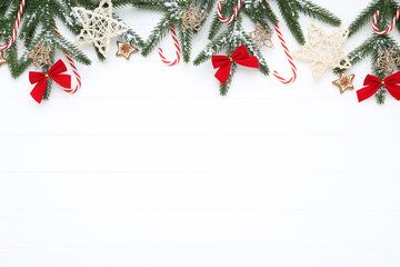 Christmas tree branches with toys and candies on white wooden table
