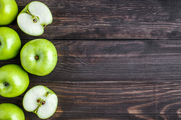 Ripe green apples and apple slices on old wooden background.Vegetables for diet and healthy eating.Organic food. Place for text. Top view