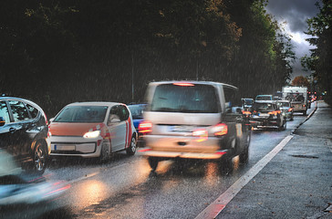 dangerous traffic in autumn, rush hour with braking cars in the rain on wet asphalt in a narrow...