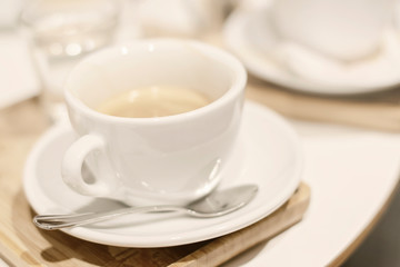 Coffee in a white cup on the table in a cafe. Selective DOF. Coffee shop blurred background. 