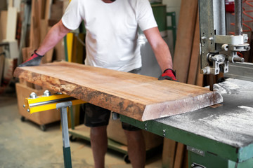 Carpenter sawing a wooden plank on a band saw