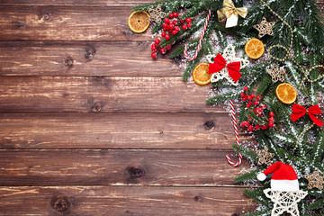 Christmas tree branches with toys and orange fruits on brown wooden table