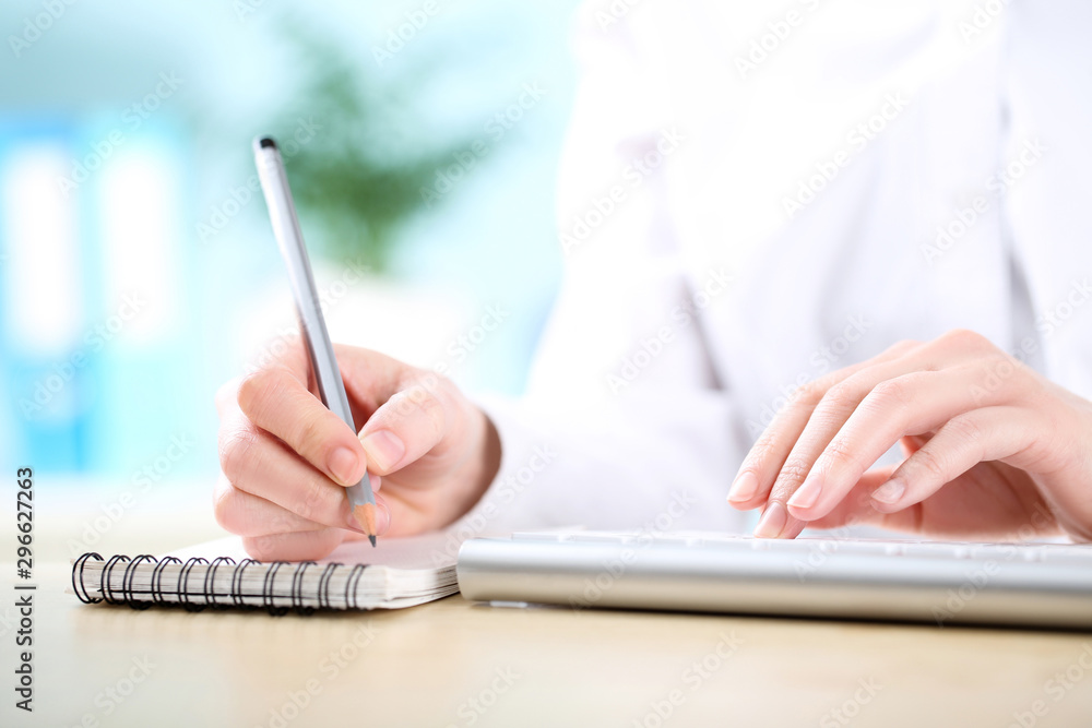 Fototapete female hands typing on computer keyboard and writing in notepad