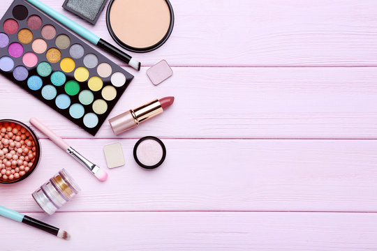 Different makeup cosmetics on pink wooden table