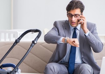 Businessman looking after newborn baby at home and teleworking