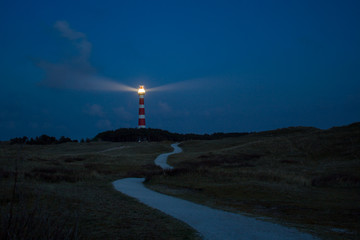 lighthouse of Ameland at night with light beaming across the deep blue sky