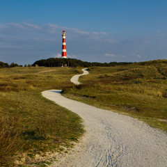 Path leading through the dunes towards vuurtoren, lighthouse of Ameland