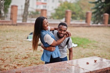 Two african students with backpack on yard of university hugs and having fun together.