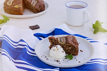 Banana bread with oatmeal and cocoa on a white ceramic plate on a light concrete background. American cuisine. Baking with banana recipes. Served with vanilla ice cream.