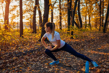 Training and exercising in autumn park. Woman stretching legs outdoors. Active healthy lifestyle