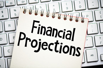Financial projections text written in a notebook located on the keyboard