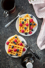 Waffles, maple sirup, blueberries and raspberries.