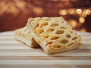 Two apple lattice on a wooden board, warm tones, blurred background. Pastry product.