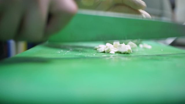 Close up of a cook cutting fresh mozzarella cheese on green teflon cutting board