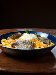 Peruvian food: Fetucinni with huancaina, cheese and grilled beef. Wooden background.