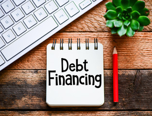 Debt financing text written in a notebook. View from above