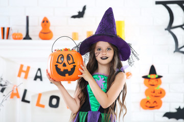 Beautiful girl in halloween costume holding pumpkin bucket