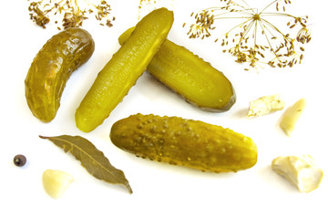 Pickled cucumbers on a white background surrounded by spices