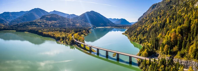 Foto auf Glas Malerische Luftaufnahme der Brücke über den Sylvensteinsee mit schönen Reflexionen. Alpen Karwendelgebirge im Rücken. Herbstlandschaft von Bayern, Deutschland © cloudless