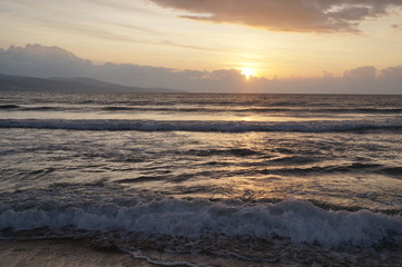 Golden natural sea sunset view of jetty or small bridge at horizon with people silhouette and orange sky landscape. Sunset or sunrise reflection in nature with sun in clouds above black sea scenery.