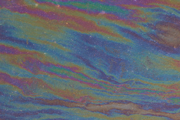 An iridescent gasoline film on the surface of an asphalt road