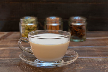 Warm indian drink with spices masala chai on brown wooden background