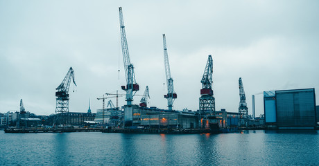 Obraz premium Photo of river, floating cranes, buildings on river bank