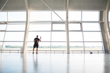 Silhouetted image of businessman with lpassport looking through window at airport