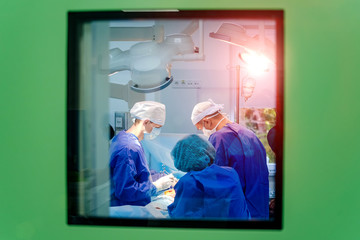 View from the window to the operating room. Process of surgery operation using medical equipment....