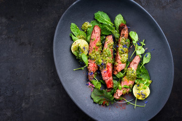 Barbecue wagyu hanging tender steak with chili, lettuce and chimichurri sauce as top view on a...