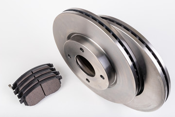 Steel brake discs and brake pads for a passenger car. New spare parts for car repairs.