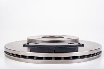 Steel brake discs and brake pads for a passenger car. New spare parts for car repairs.