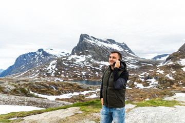 Handsome happy young man outside in free alternative vacation camping talking by mobile phone.