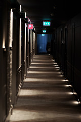 Corridor in the hotel with room illumination and evacuation exit badges