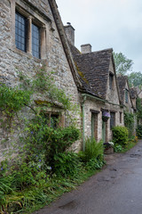BIBURY, COTSWOLDS, UK - MAY 28, 2018: Traditional cotswold stone cottages built of distinctive yellow limestone in the world famous Arlington Row, Bibury, Gloucestershire, England   