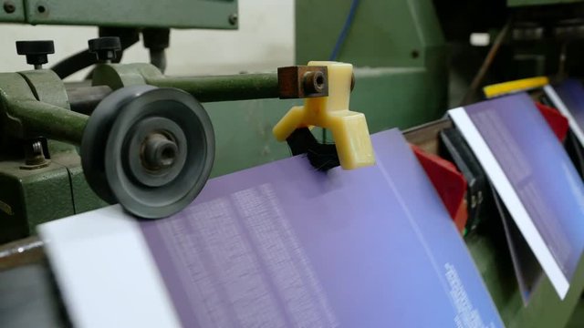 Old vintage printing press is working draws paper in printing factory.