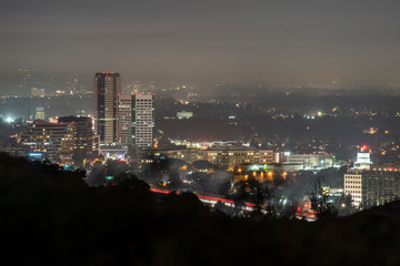 Fototapeta premium Foggy night view of the Burbank media district in the San Fernando Valley area of Los Angeles, California. Shot from hilltop in popular Griffith Park. 