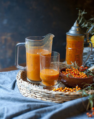 Brown table with common sea buckthorn drink and berreis Homemade sea buck thorn liqueur, Hippophae rhamnoides, on the wooden board.  Brown tabl sea buckthorn pumpkin smoothie, fresh vegan autumn drink