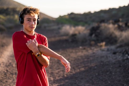 one teenager isolated alone at mountain stretching after doing exercise and some sport outdoors like running and jogging - adult fitness hearing music with headphones - Powered by Adobe