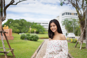 A beautiful Japanese woman wearing a white dress, walking happily in the green lawn. In the light of the sun