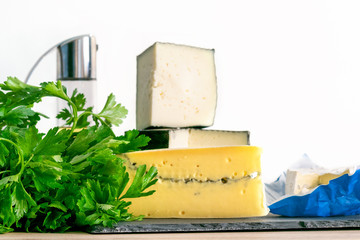 various types of cheese with parsley and olive oil on the table.