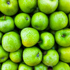 Background of green apples in the market. Ripe fruits on the counter.