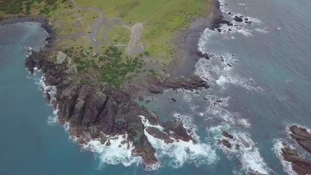 Flyover of rocky shoreline meeting Aorangi Ranges in New Zealands North Island