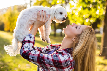 Beautiful woman spending time with her Maltese dog outdoor.