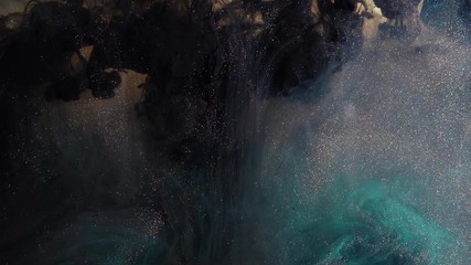 Abstract bronze paint mixed with different multi-colored paints in water in slow motion. Inky cloud swirling flowing underwater. Abstract smoke explosion