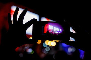 Silhouette of people holding their smart phones and photographing concert.