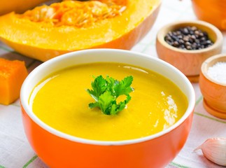 The pumpkin soup served on the table in bowl