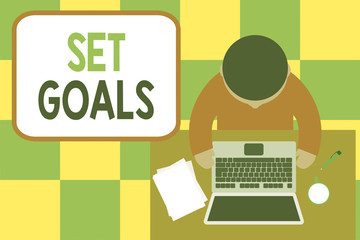 Conceptual hand writing showing Set Goals. Concept meaning Defining or achieving something in the future based on plan Upper view young man sitting table laptop coffee cup pen